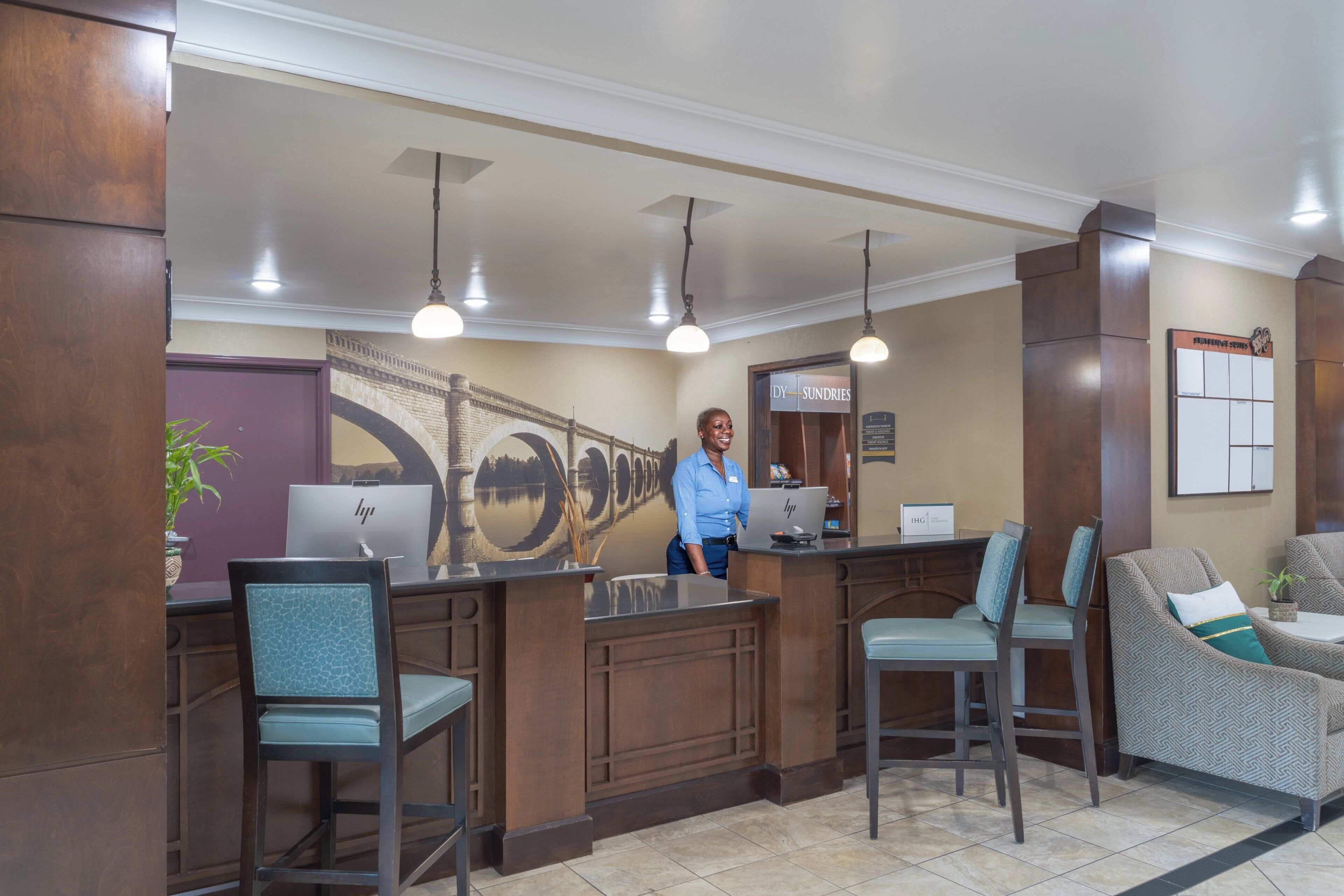A reception area with a receptionist, a desk with a laptop, a seating area with chairs, and a wall mural.