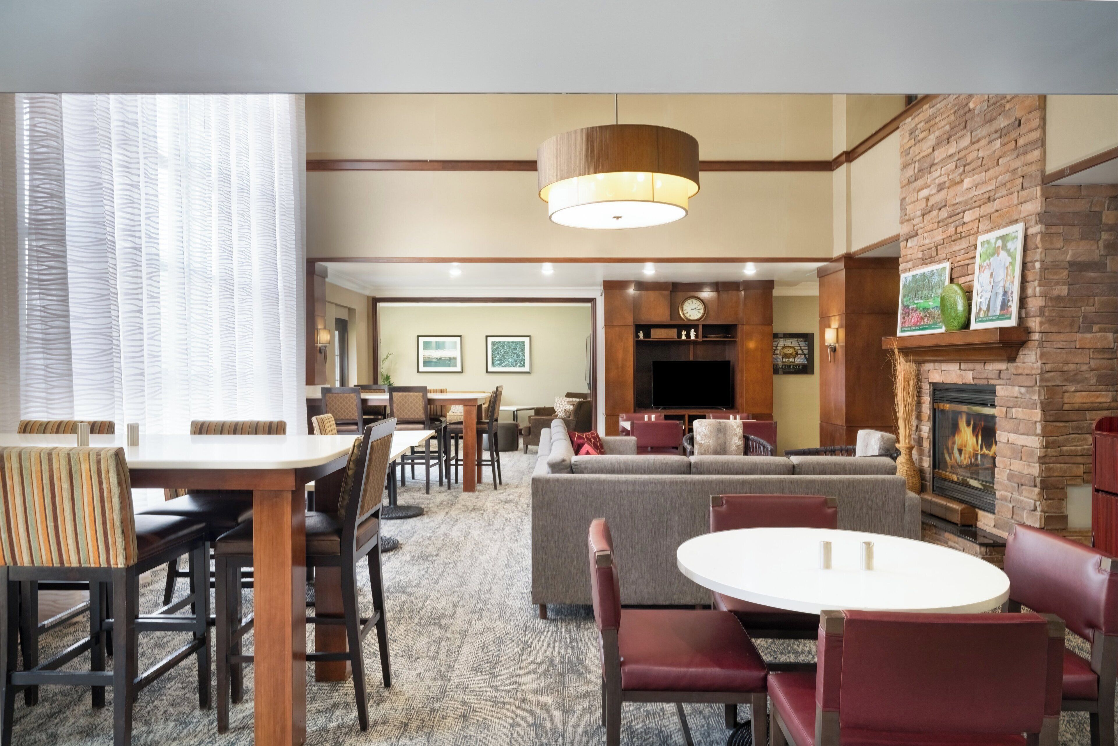 A hotel lobby with a dining area, sofas, a fireplace, and a television.