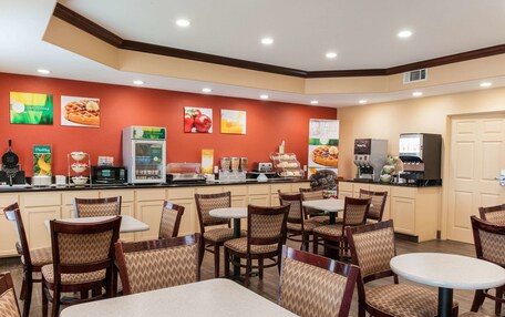 A restaurant with a counter, seating, and various food displays.