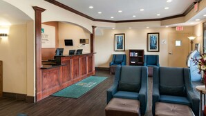 A hotel lobby with a reception desk, seating area, and framed pictures on the walls.