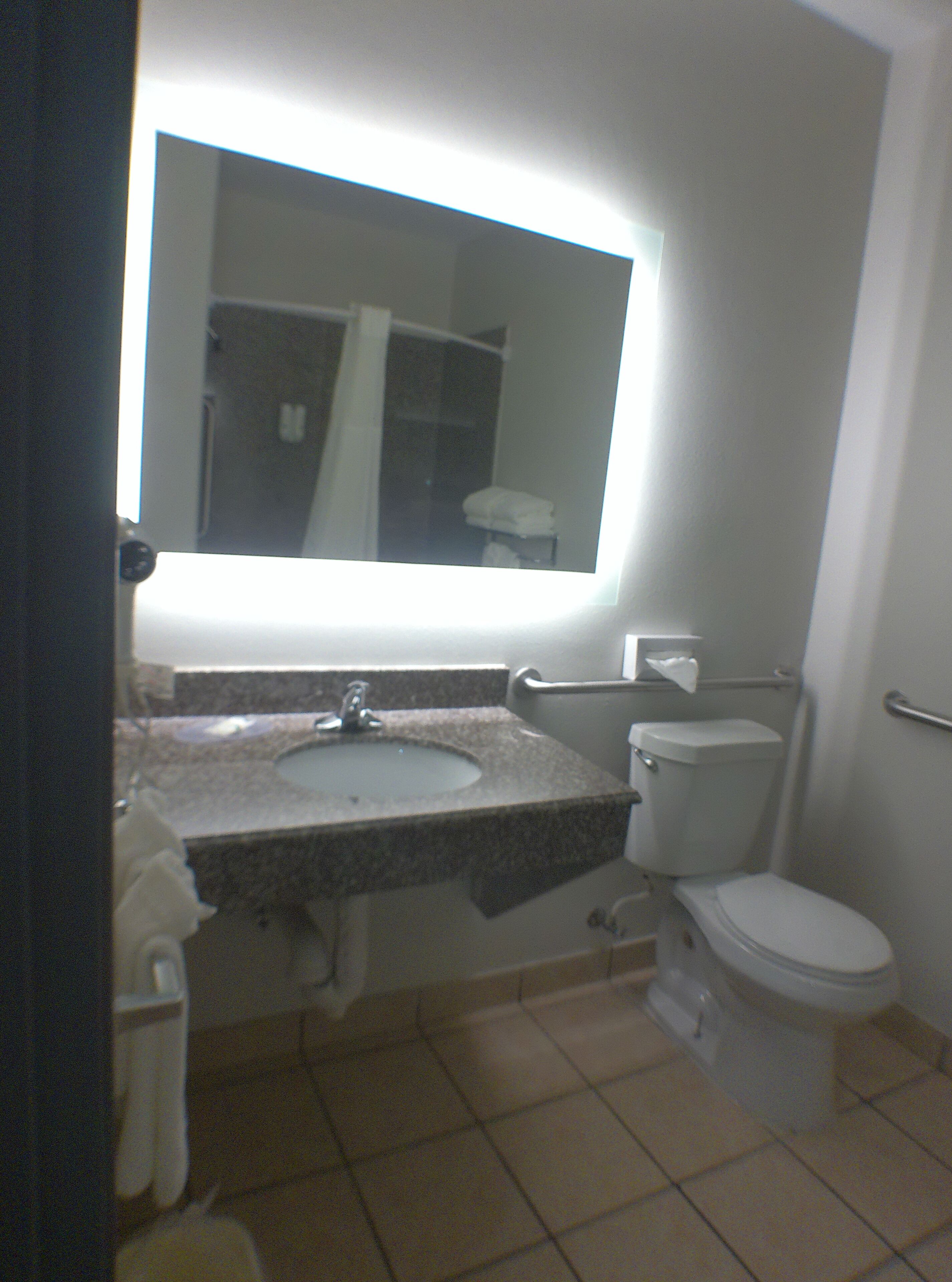 A bathroom with a sink, toilet, and a large mirror above the sink.