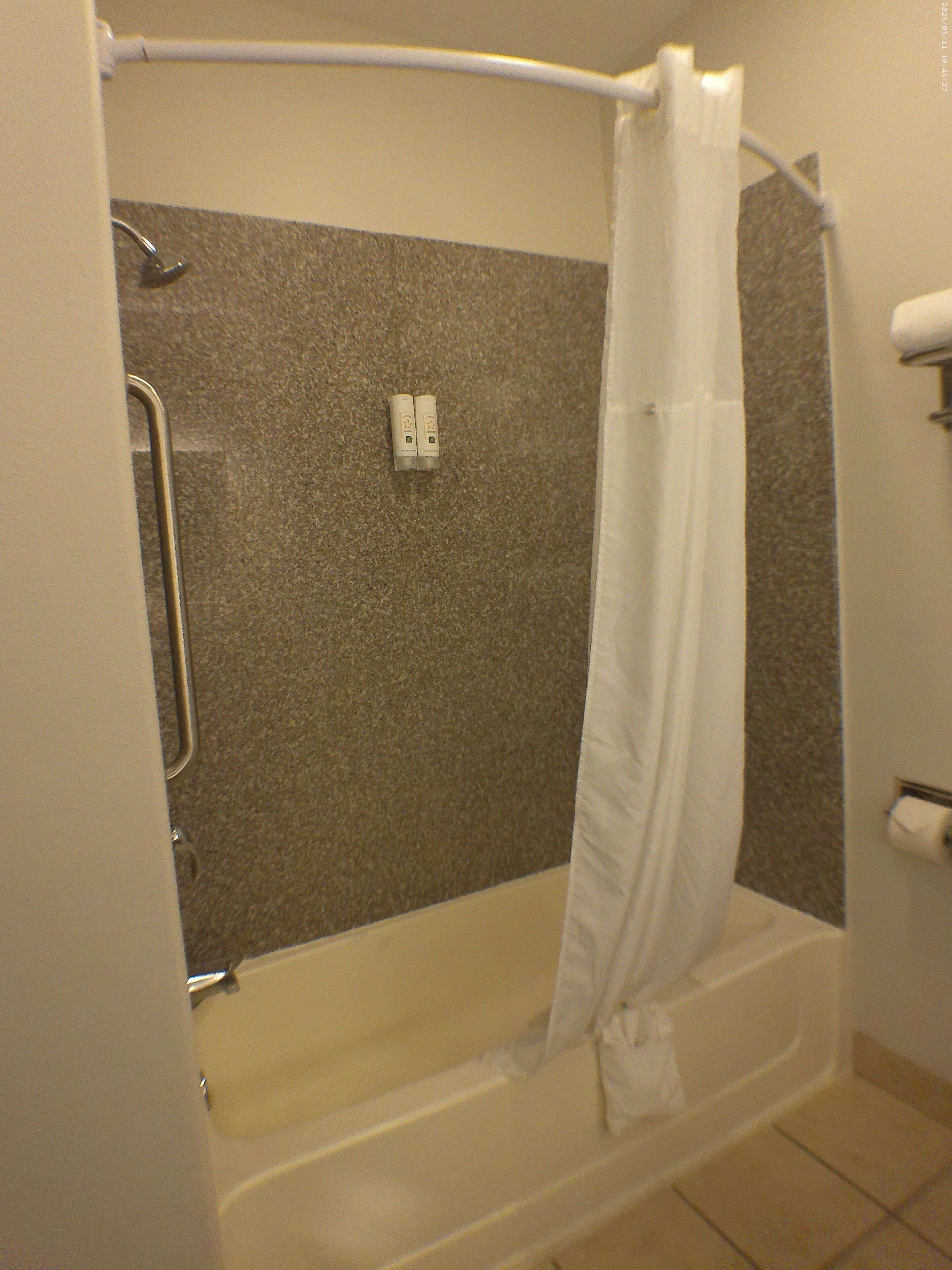 A bathroom with a bathtub, a shower curtain, and a towel rack.