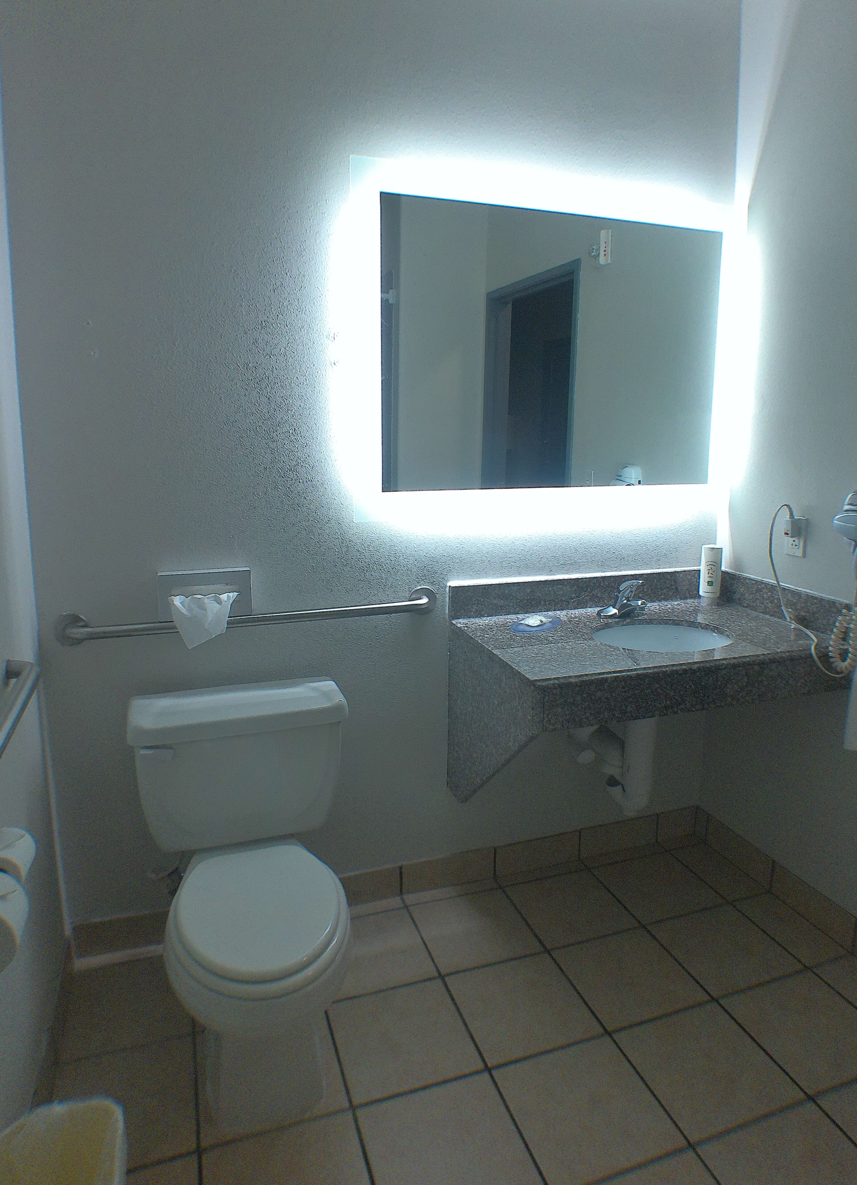 A bathroom with a toilet, sink, and mirror.