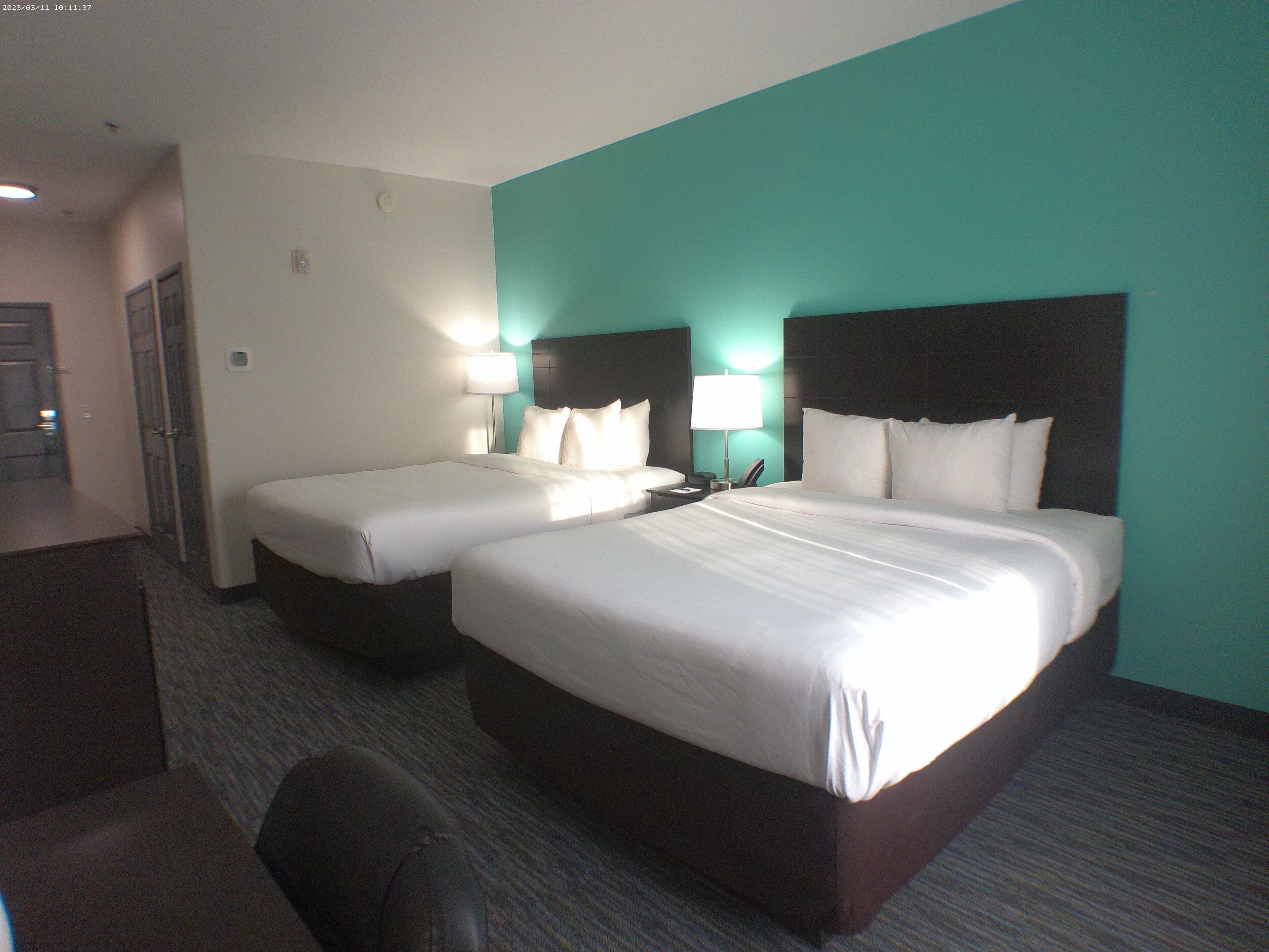 Een hotelkamer met twee bedden, een bureau en een stoel.