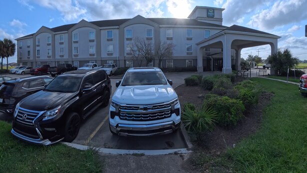 A hotel with a parking lot, a covered entrance, and a clear sky.
