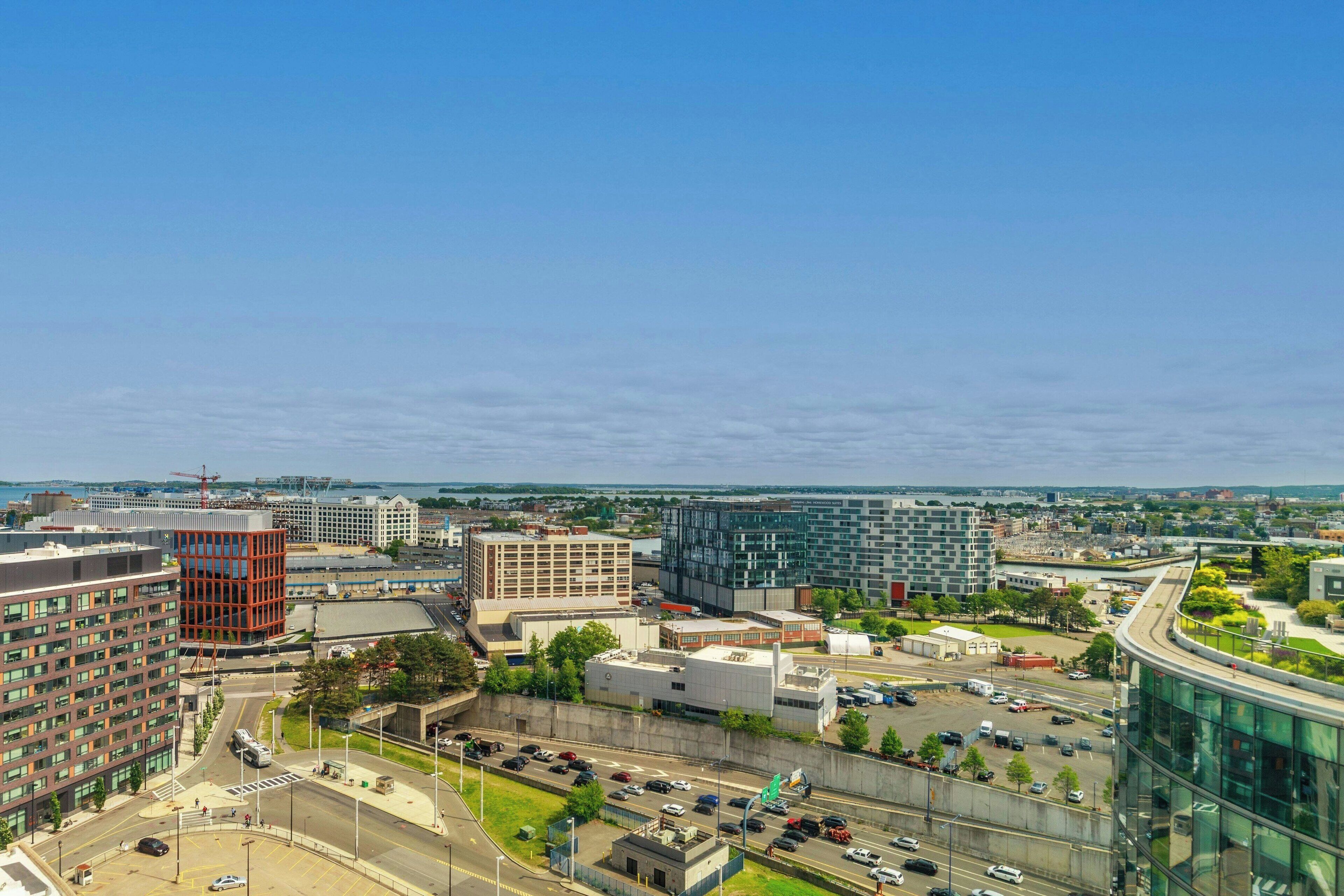 Un paysage urbain avec des bâtiments modernes, un rond-point et une zone de stationnement.