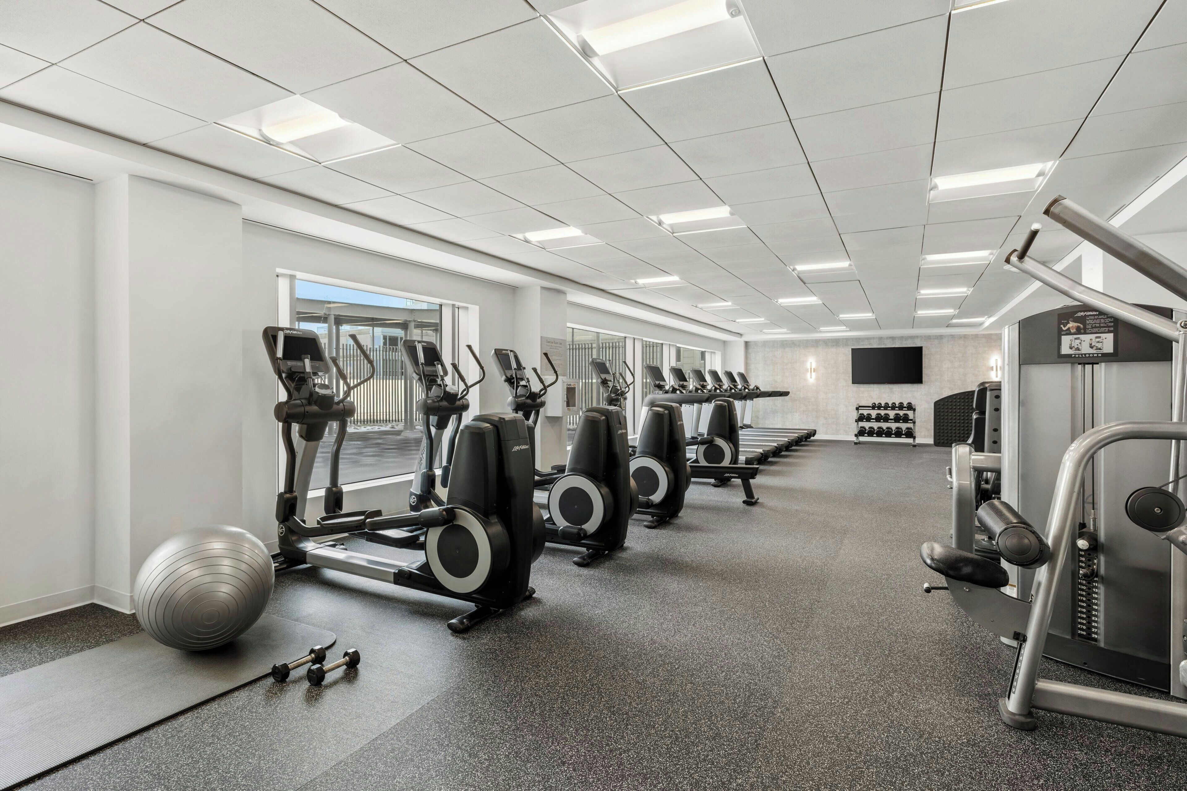 A gym with treadmills, elliptical machines, and weight equipment.