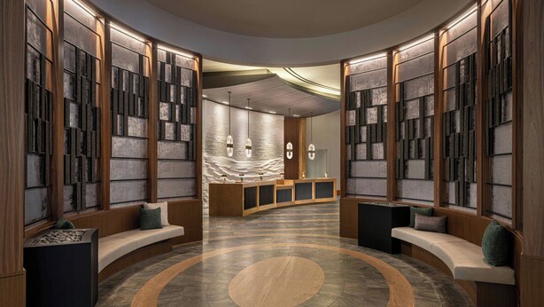 A lobby with curved seating, a central circular design on the floor, and a reception desk with a marble counter. - Renaissance® Boston Seaport District (Boston)