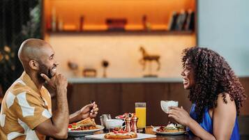 Una pareja cenando en una mesa con una estantería al fondo.