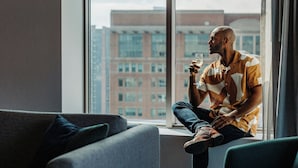 A person sitting by a window with a city view, holding a glass. - Renaissance® Boston Seaport District (Boston)