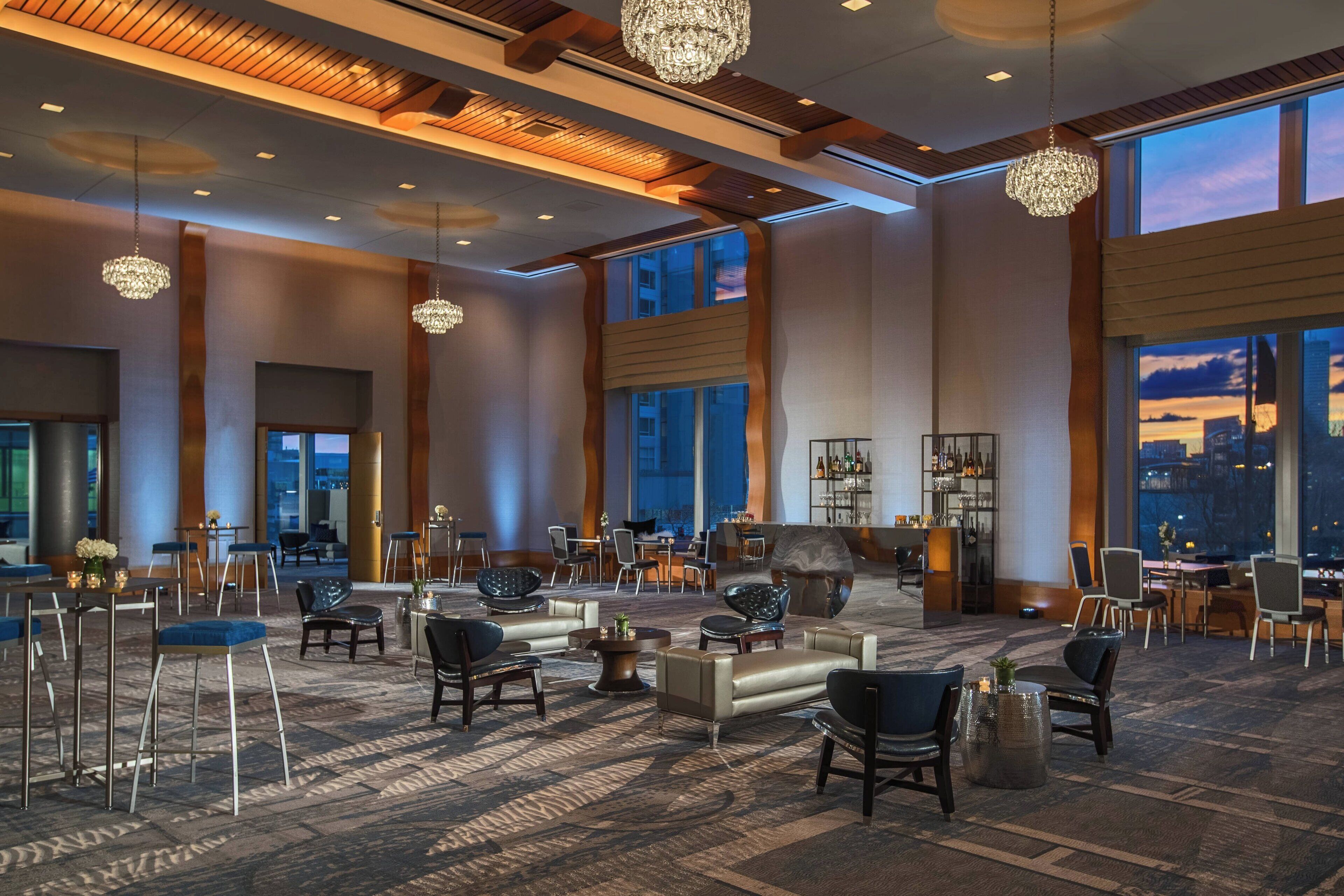 A spacious lobby with high ceilings, large windows, and elegant chandeliers.