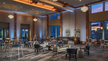 A spacious lobby with high ceilings, large windows, and elegant chandeliers.