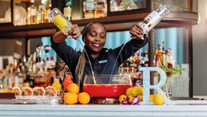 A bartender at a bar with a variety of bottles and a large 'R' decoration. - Renaissance® Boston Seaport District (Boston)