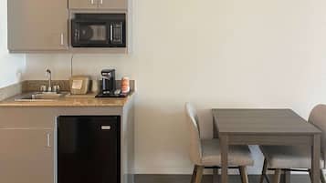 A compact kitchen with a microwave, toaster, coffee maker, and a small refrigerator.