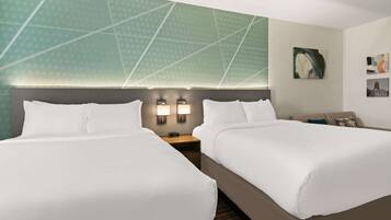 A hotel room with two beds, a nightstand with a clock, and a wall with a geometric pattern.