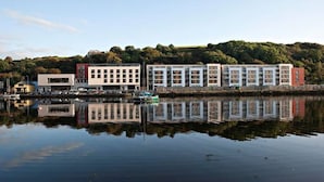 A waterfront hotel with multiple buildings, a dock, and a calm lake reflecting the structures.