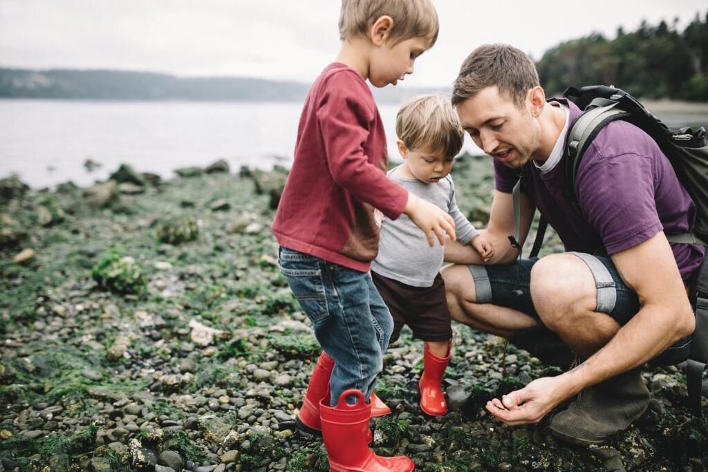 A family by a rocky shore with a lake in the background.