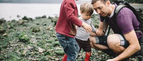 Una familia junto a una costa rocosa, con un lago al fondo.