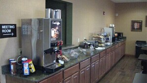 A kitchenette with a refrigerator, coffee machine, and a microwave. There is a sign indicating a meeting room. - Randolph Inn and Suites (Winchester)