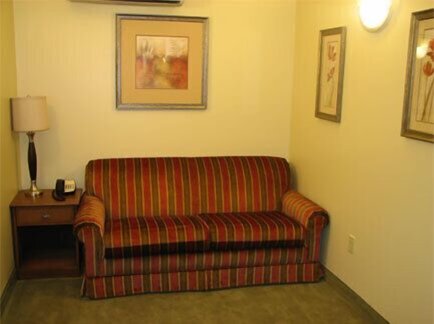 A striped sofa in a room with a lamp and a framed picture on the wall.