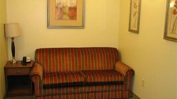 A striped sofa in a room with a lamp and a framed picture on the wall.