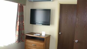 Um quarto com um armário de madeira, uma televisão na parede e uma porta.