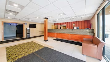 Un vestíbulo de hotel con una recepción, un espacio de descanso y un amplio ventanal.