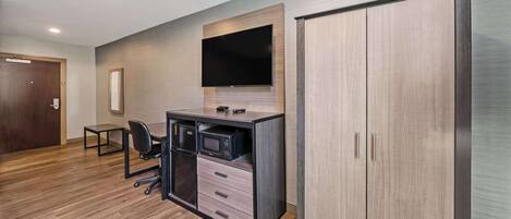 A modern office space with a wooden desk, a flat-screen TV, a cabinet, and a wardrobe.