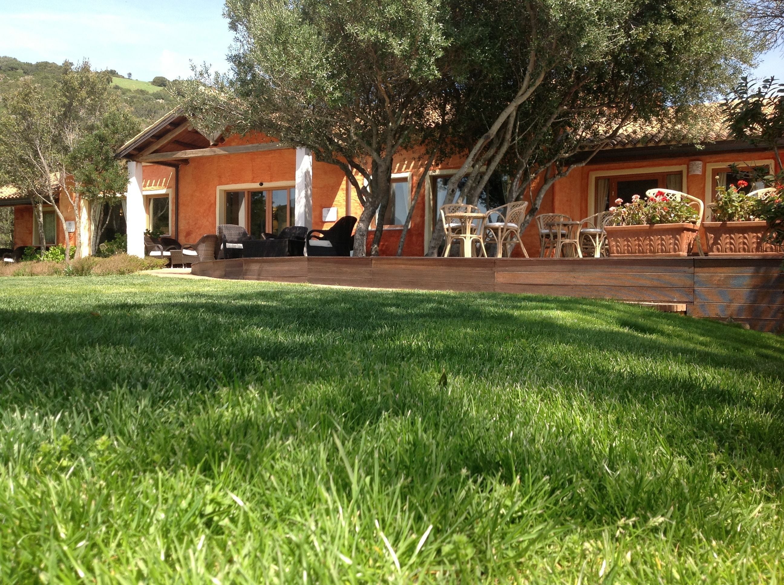 A rustic house with a patio area, outdoor seating, and a well-maintained lawn.