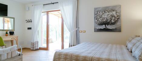 Un dormitorio con una cama, un escritorio con silla, una ventana con cortinas y un cuadro en la pared.