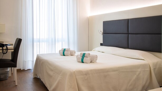 Una habitación de hotel con una cama, un escritorio y una silla.