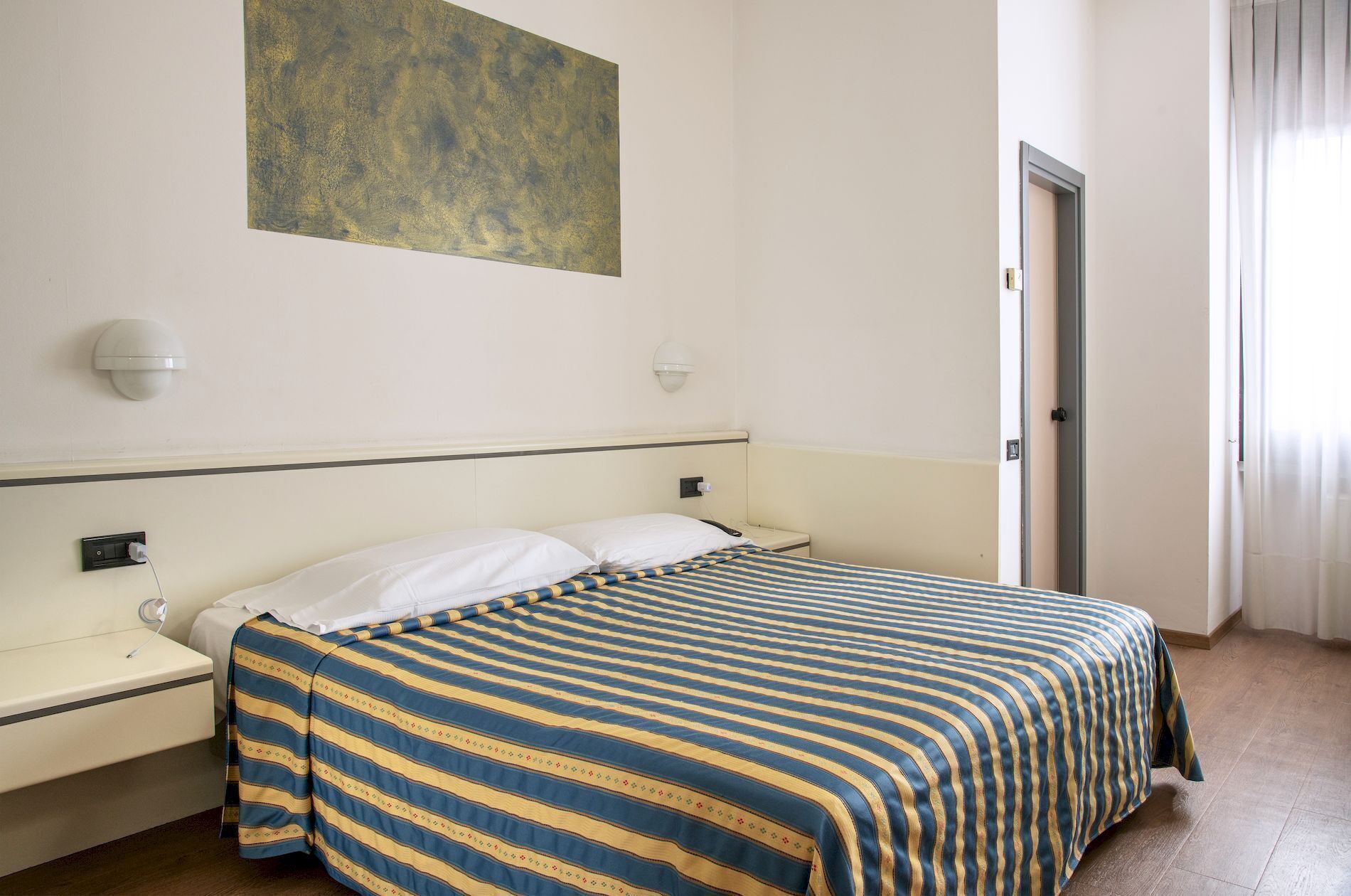 Ein Hotelzimmer mit Bett, Nachttisch und einer Wandleuchte.