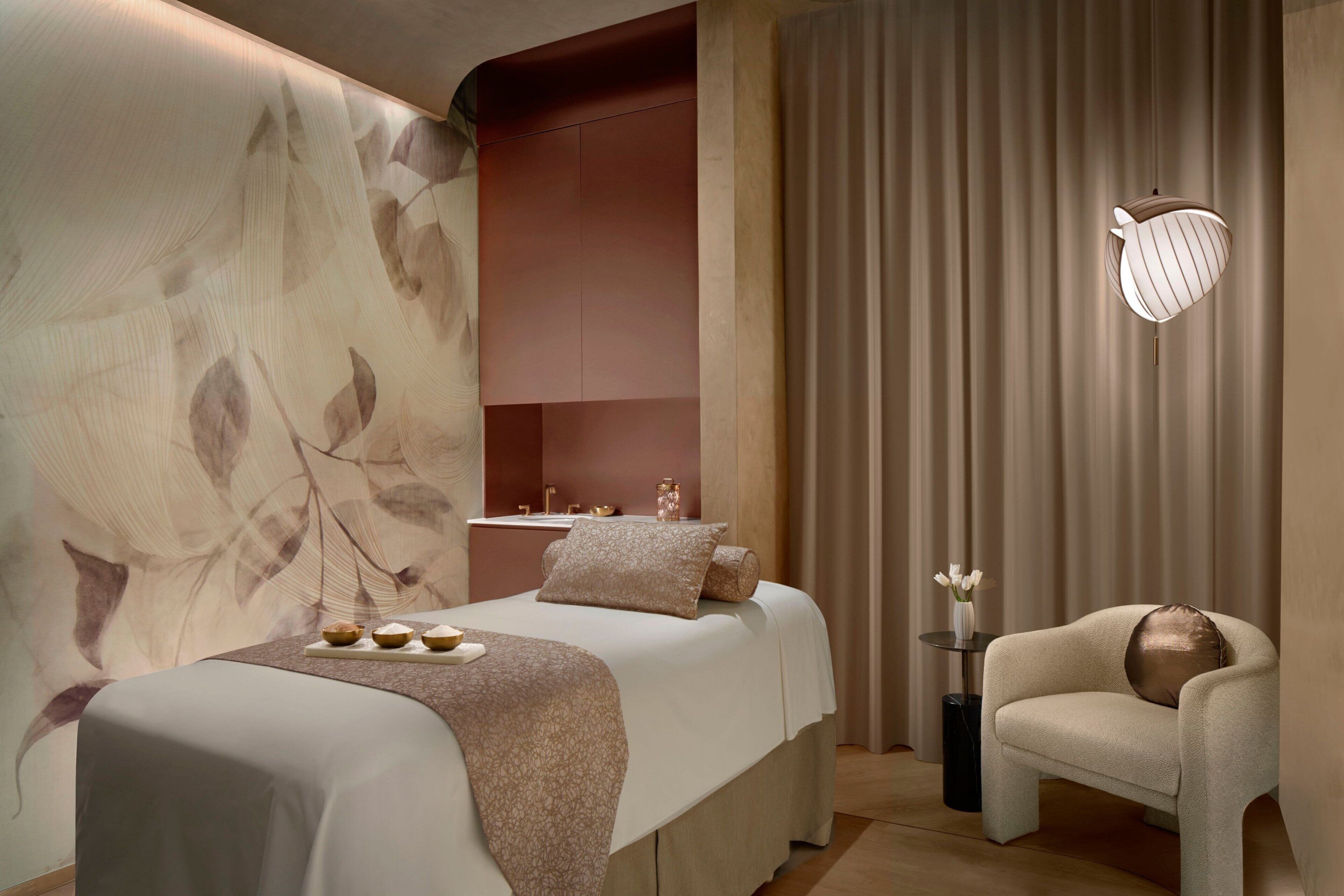 A modern bedroom with a large bed, a side table with a vase, and a chair.