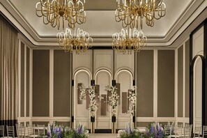 A formal dining room with chandeliers, floral arrangements, and a symmetrical layout.