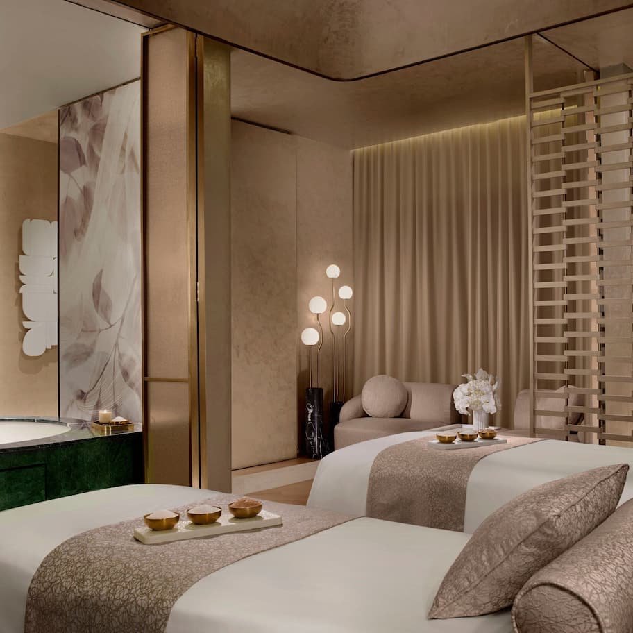 A modern hotel room with two beds, a large mirror, a vanity, and a decorative wall panel.