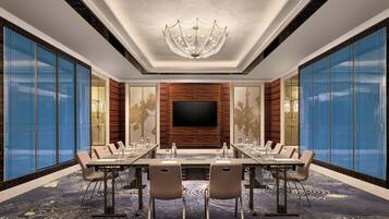 A conference room with a large flat-screen TV, a chandelier, and a patterned carpet.