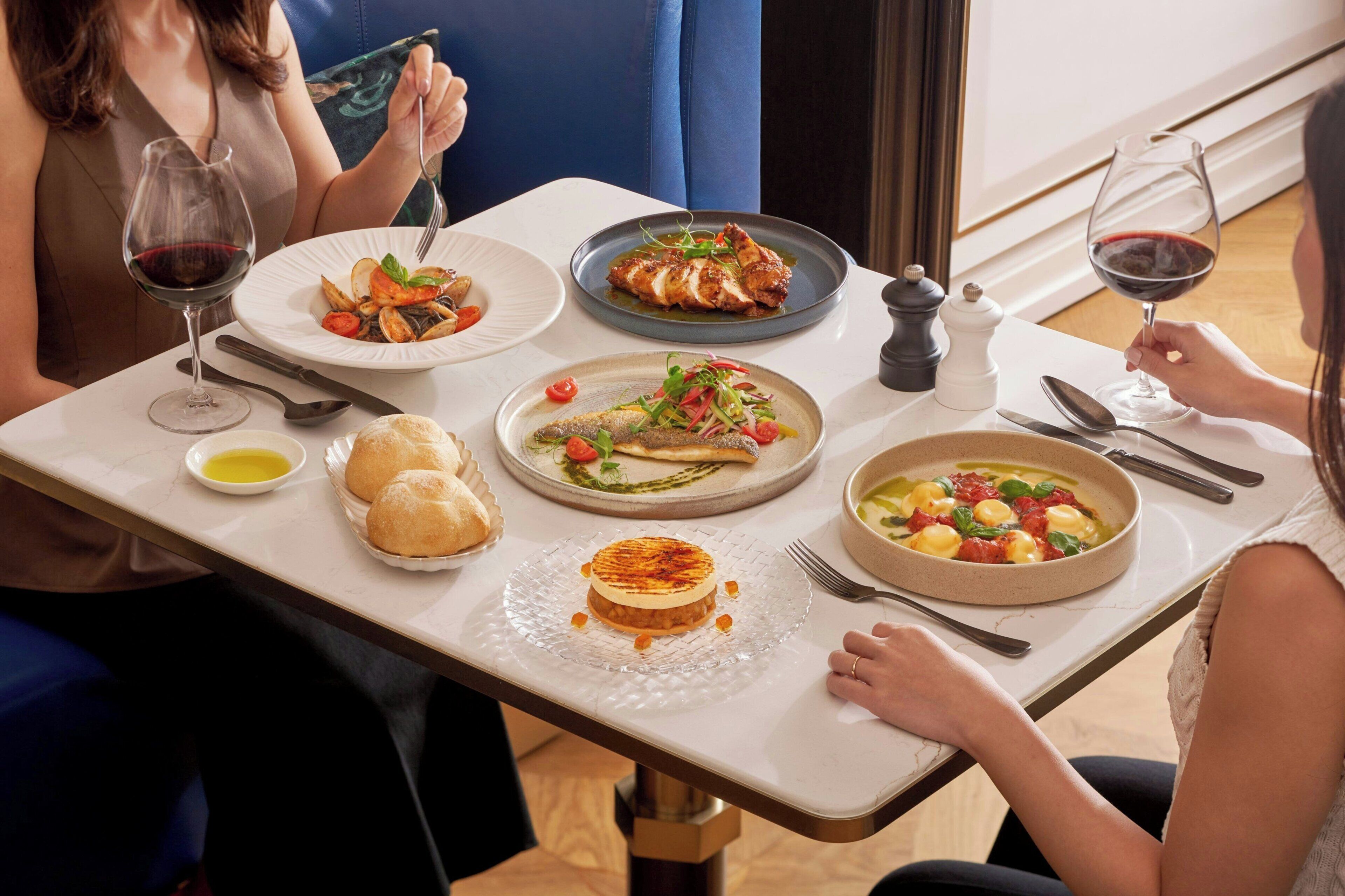 A dining table with various dishes, wine glasses, and cutlery.