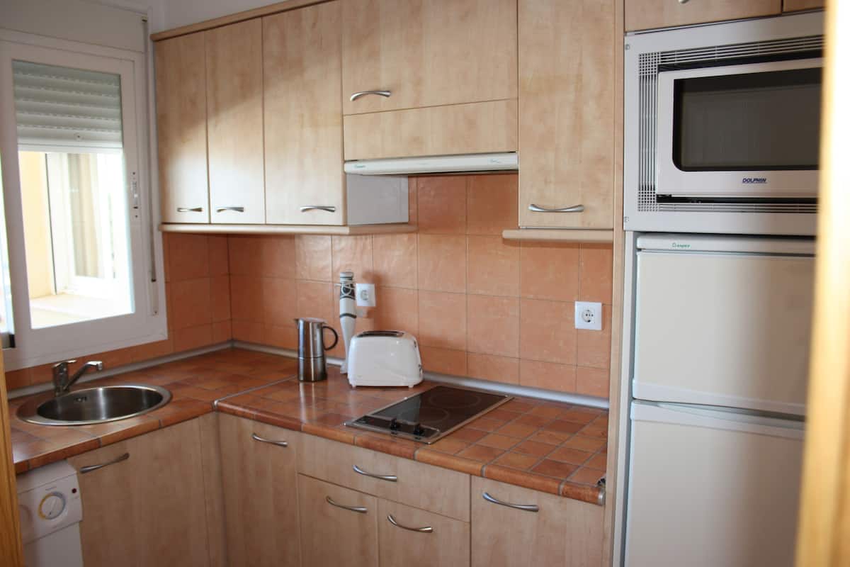 A kitchen with wooden cabinets, a built-in microwave, a toaster, and a sink.