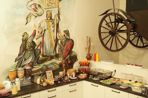Ein Buffet mit verschiedenen Speisen und einer Wandmalerei historischer Persönlichkeiten.