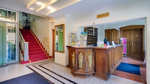 A reception area with a red carpeted staircase, a reception desk with a sign, and a wooden door.
