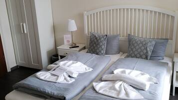 Una cama doble con dos almohadas, una mesita de noche con lámpara y un armario.