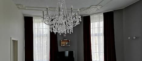 A living room with a chandelier, a television, a sofa, and a cabinet.