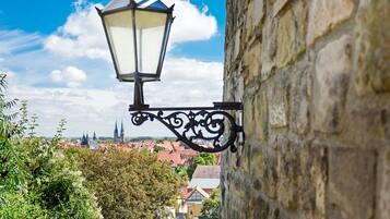 A street lamp attached to a stone building with a view of a town in the background.