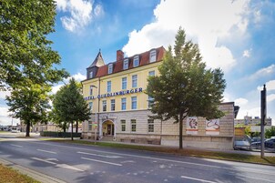 Ein Hotel mit gelber Fassade, auf der das Schild "HOTEL QUEDLINBURGER" zu sehen ist.