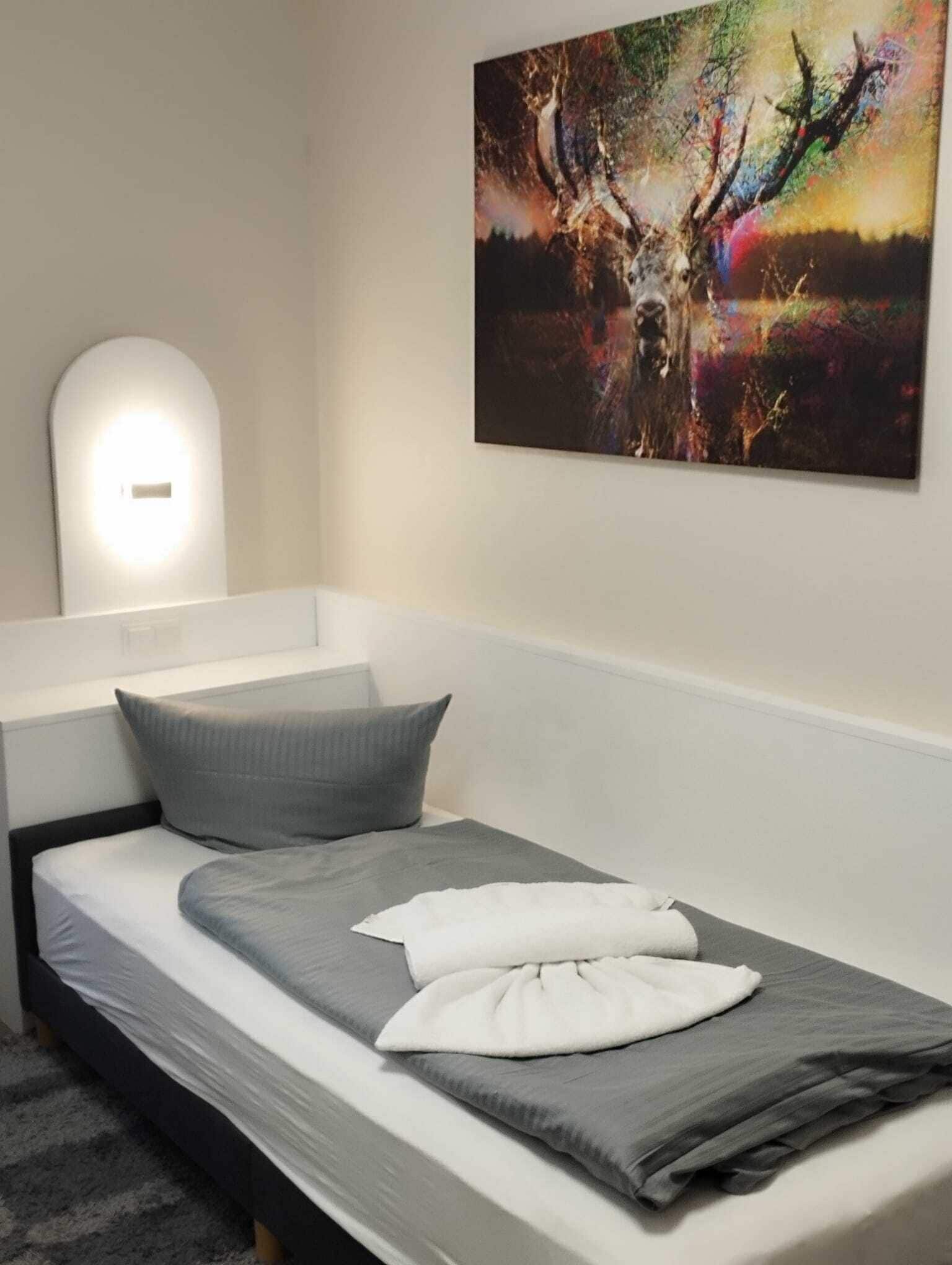 Un dormitorio con cama, almohadas, una lámpara de pared y un cuadro.