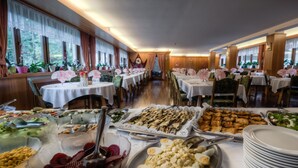 Montaje de bufé con diversos alimentos y mesas dispuestas en un comedor.