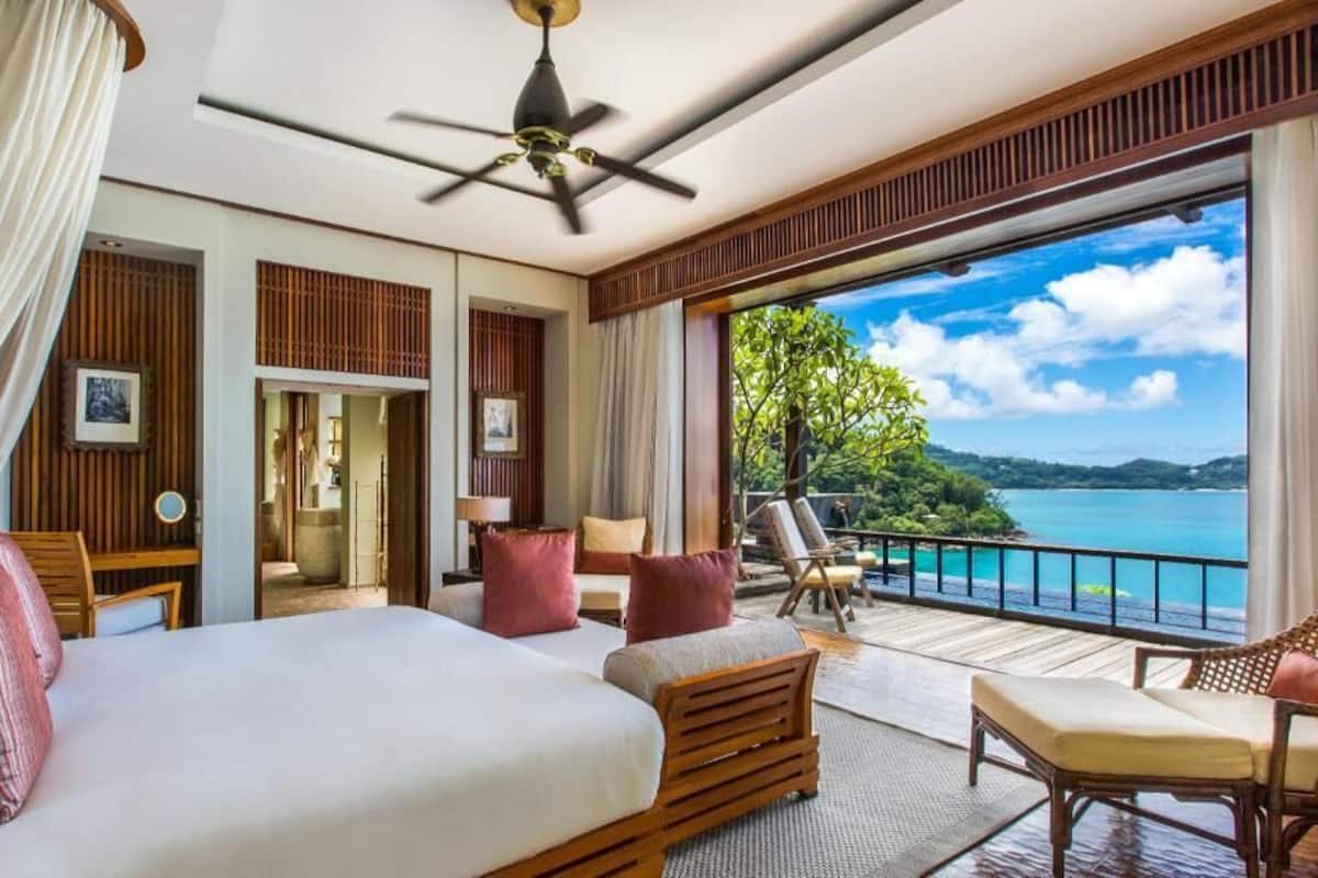 Une chambre d’hôtel comprenant un lit, un coin salon et un balcon avec vue sur la mer.