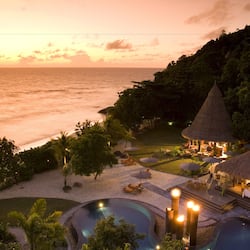 Relax by the pool or enjoy a meal at the thatched-roof dining area with ocean views.
