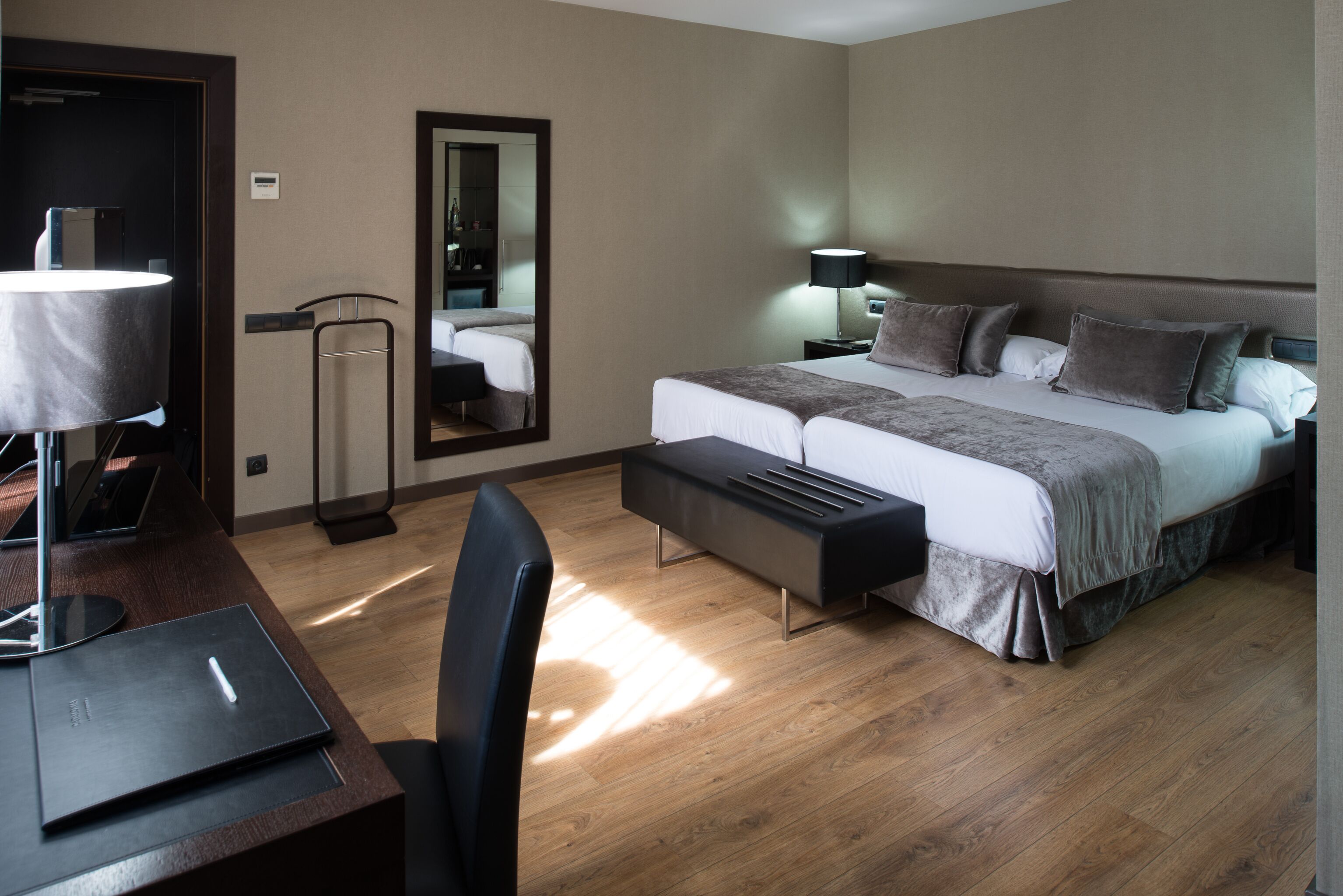 A modern hotel room with a large bed, bedside tables, a desk, and a chair.