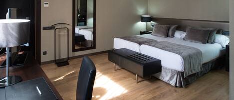 A modern hotel room with a large bed, bedside tables, a desk, and a chair.